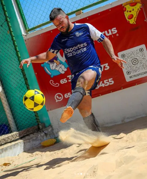 Jogador chutando bola de futevôlei na areia da Orla Beach Center